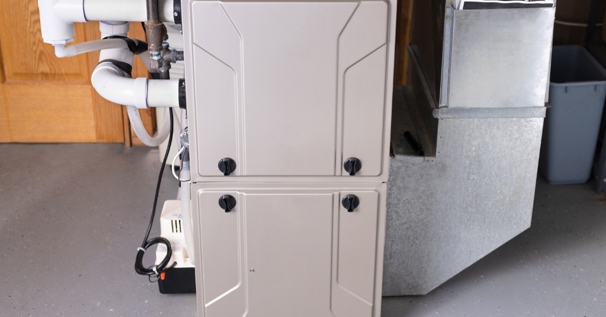 Residential furnace and ductwork system installed in a basement with exposed pipes and metal ventilation ducts.