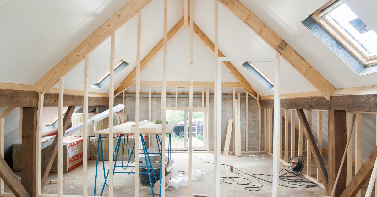 An unfinished room with wood framing, insulation, brick, and renovation materials arranged inside the space.